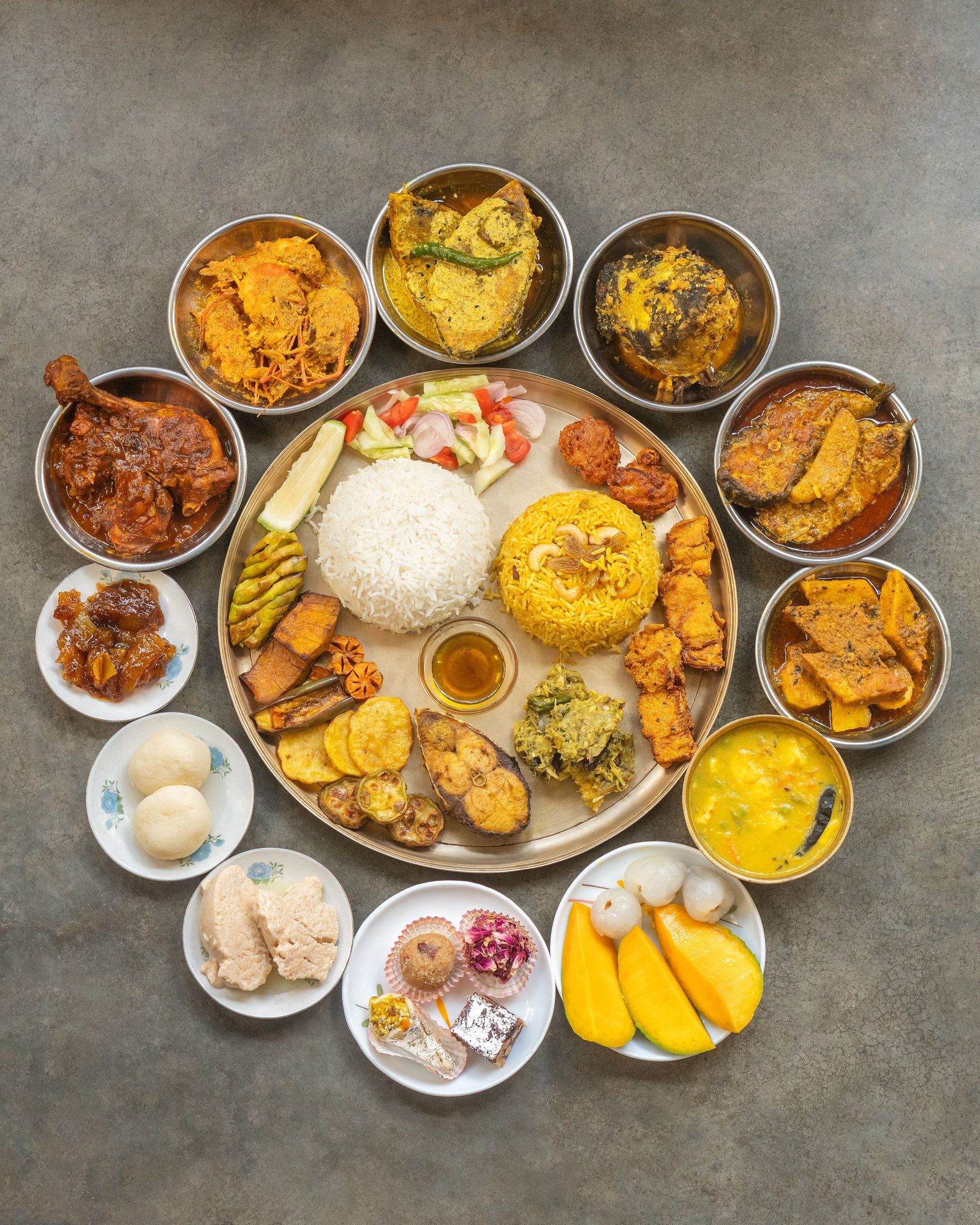 A thali seen from above with several small bowls of different dishes arranged on one plate.