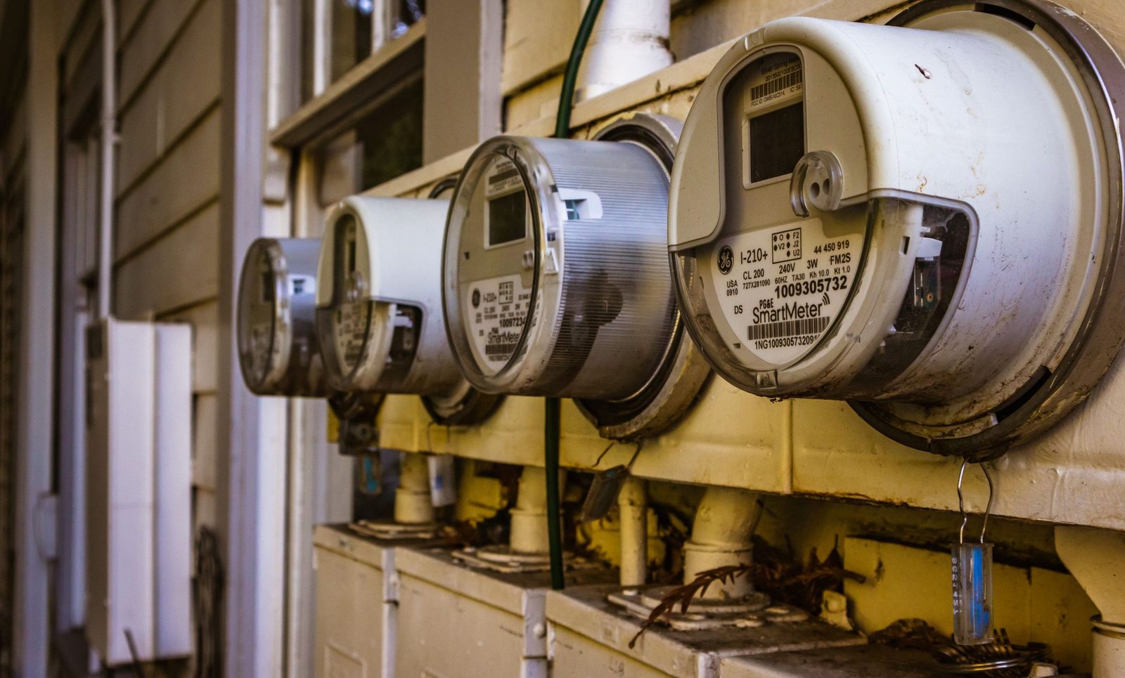A bank of electricity meters mounted on the outside wall of a residential building.
