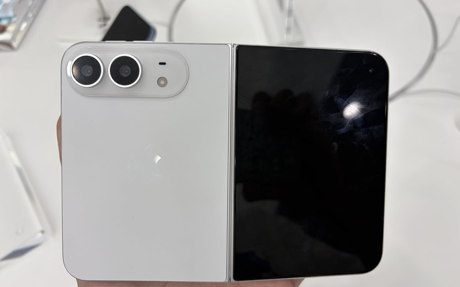 A half-open iPhone Duo showing its white back with two cameras on one side and the dark inner screen on the other