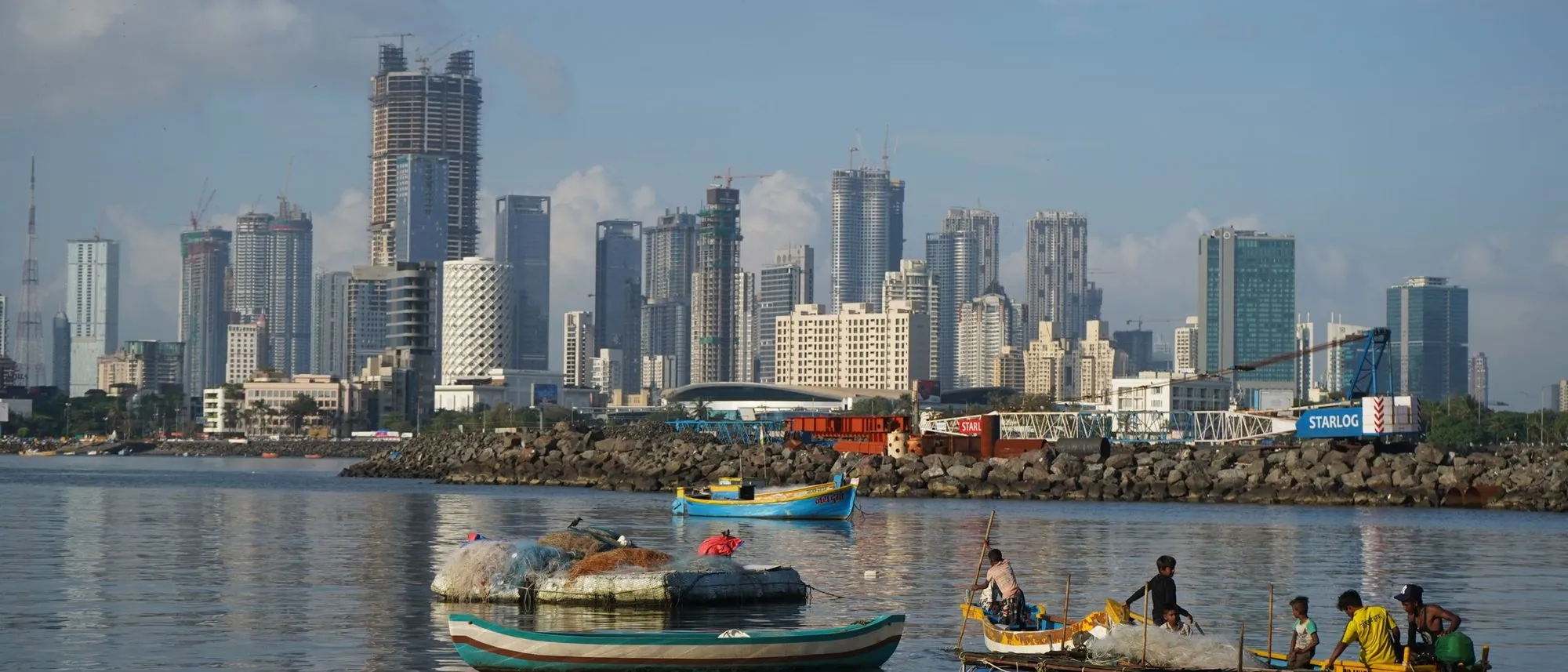 Fishing boats on the water in front of the Mumbai skyline.