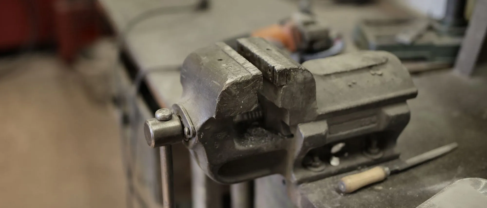 A metal vice and assorted hand tools on a workbench, seen from above