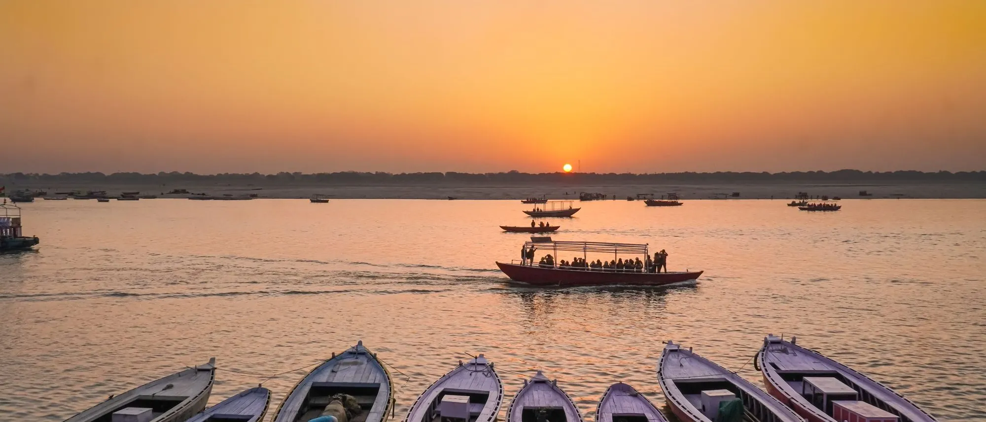 Wooden boats lined up along the Ganges at Varanasi at sunset.