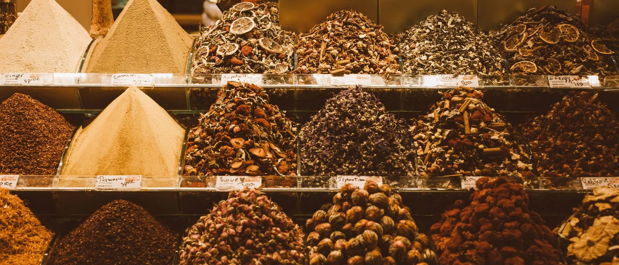 Heaps of whole and ground spices displayed side by side in a market shop.