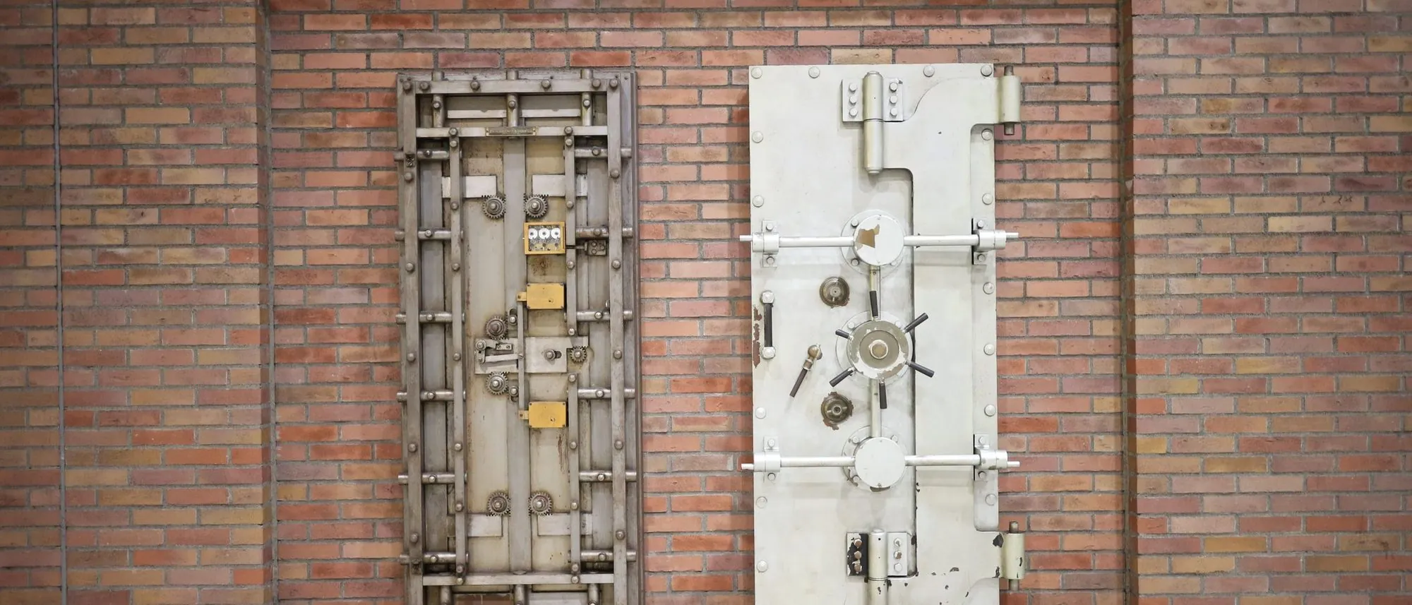 Two heavy steel vault doors set into an old brick wall.