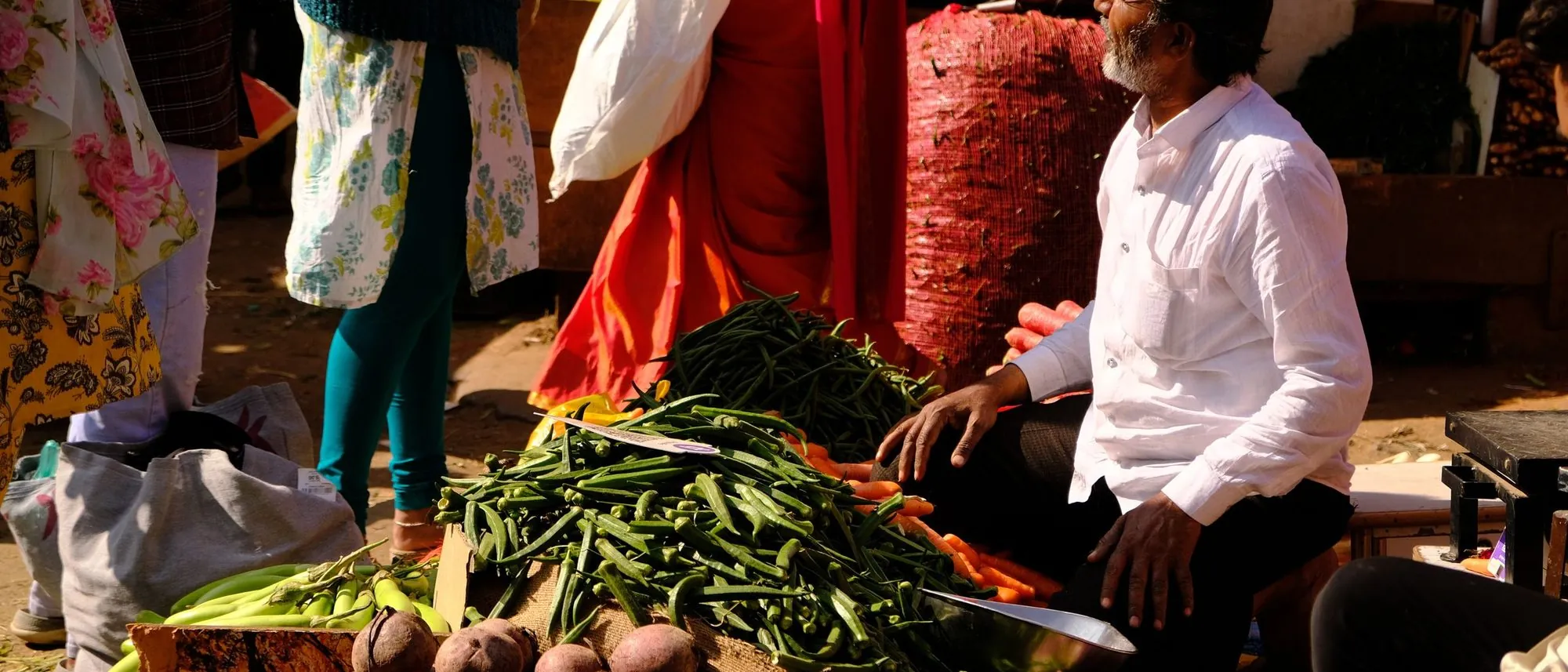Shoppers move between produce stalls at a vegetable market in Bengaluru.