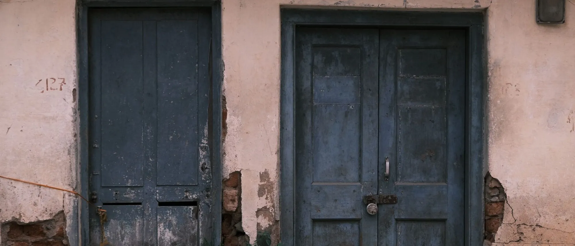 Weathered blue doors set into an old rustic wall in Bengaluru.