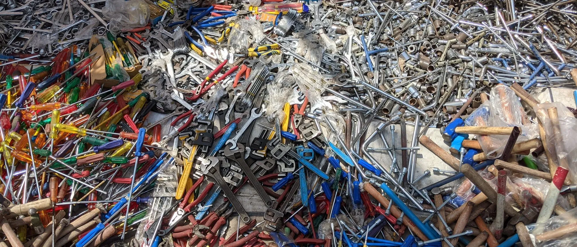 Assorted metal hand tools lie spread out at an outdoor market in Lucknow.