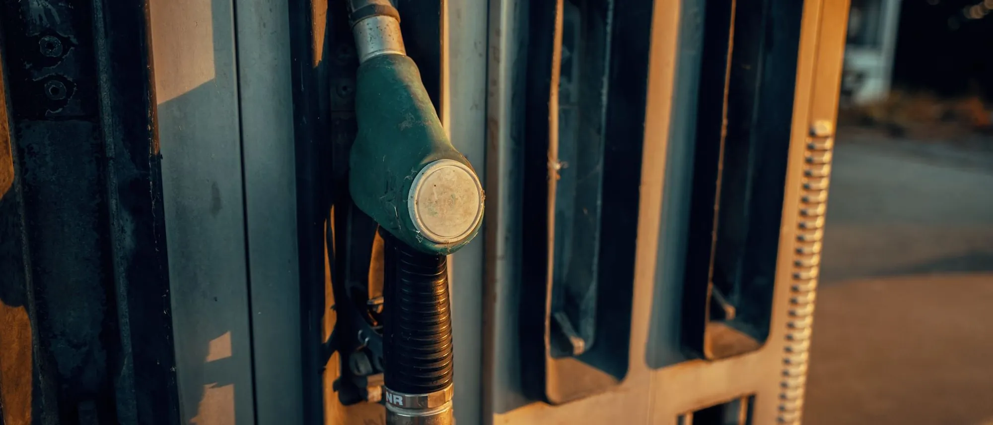 A fuel pump nozzle rests in its holder as the sun sets behind it.