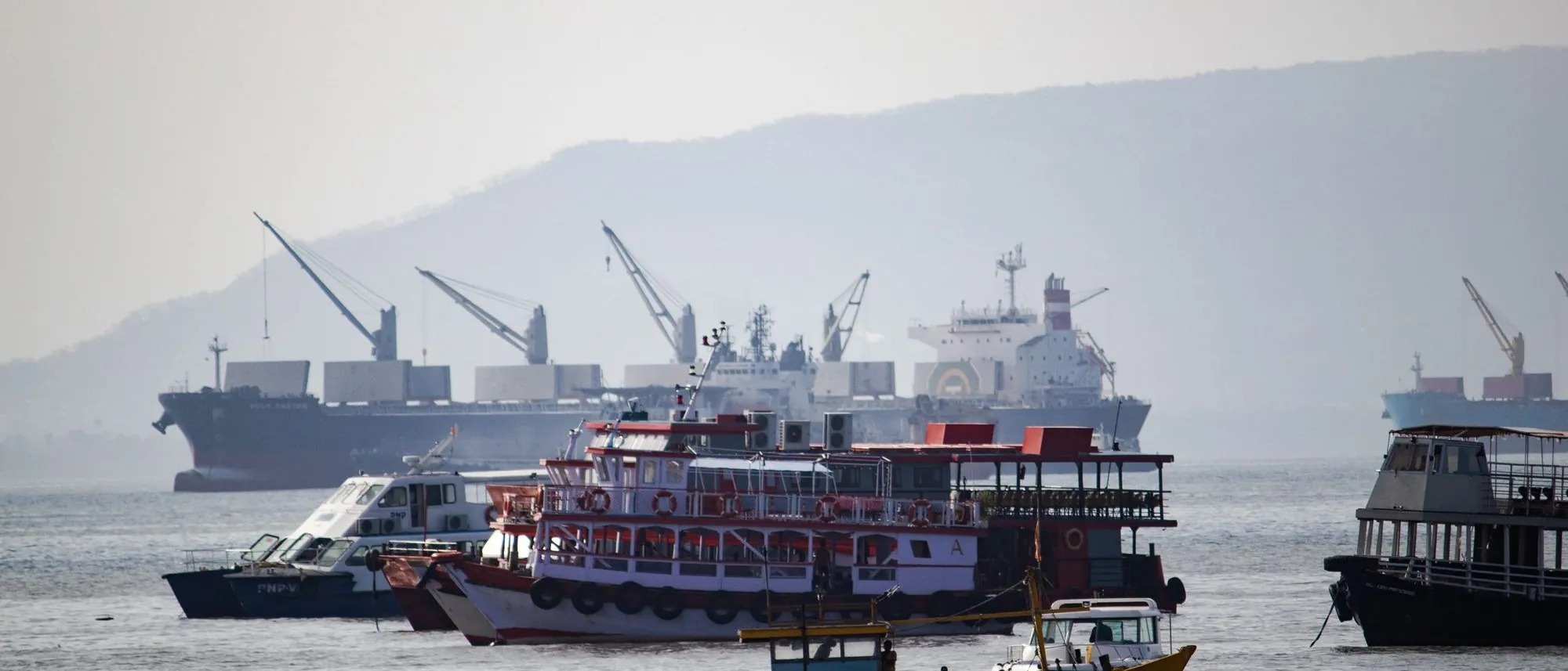 Boats and a cargo ship at anchor in the Arabian Sea off Mumbai.