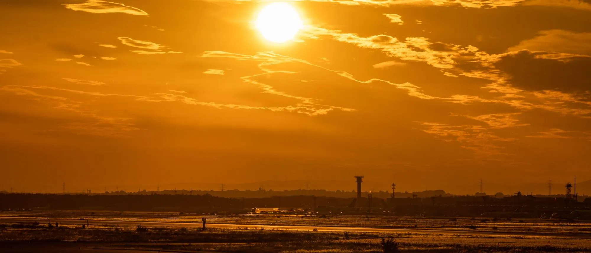 An airport runway under a golden sunset sky.
