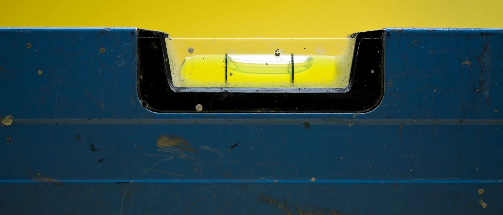 The bubble of a blue spirit level against a yellow ground