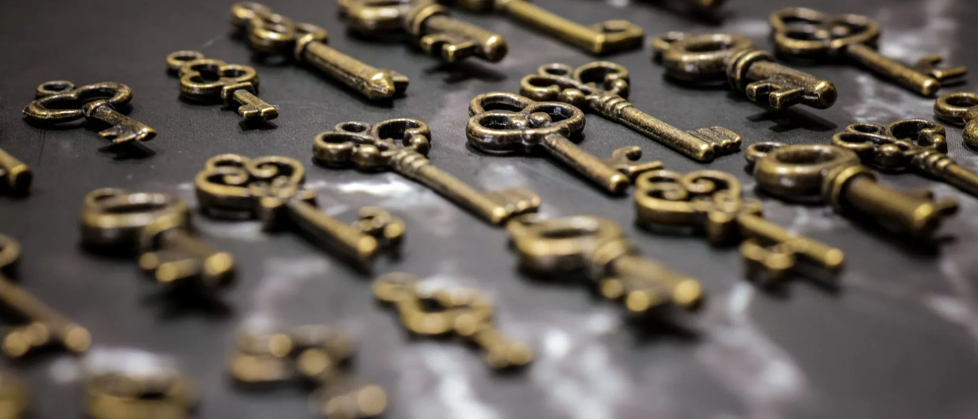 Vintage brass keys scattered across a dark surface.