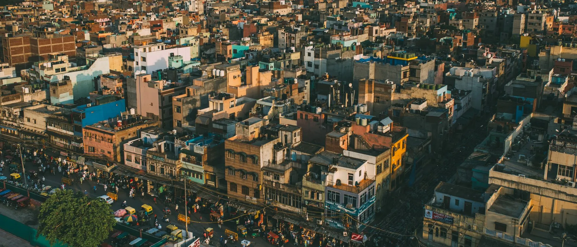 Aerial view of dense Old Delhi rooftops and a busy street in warm light