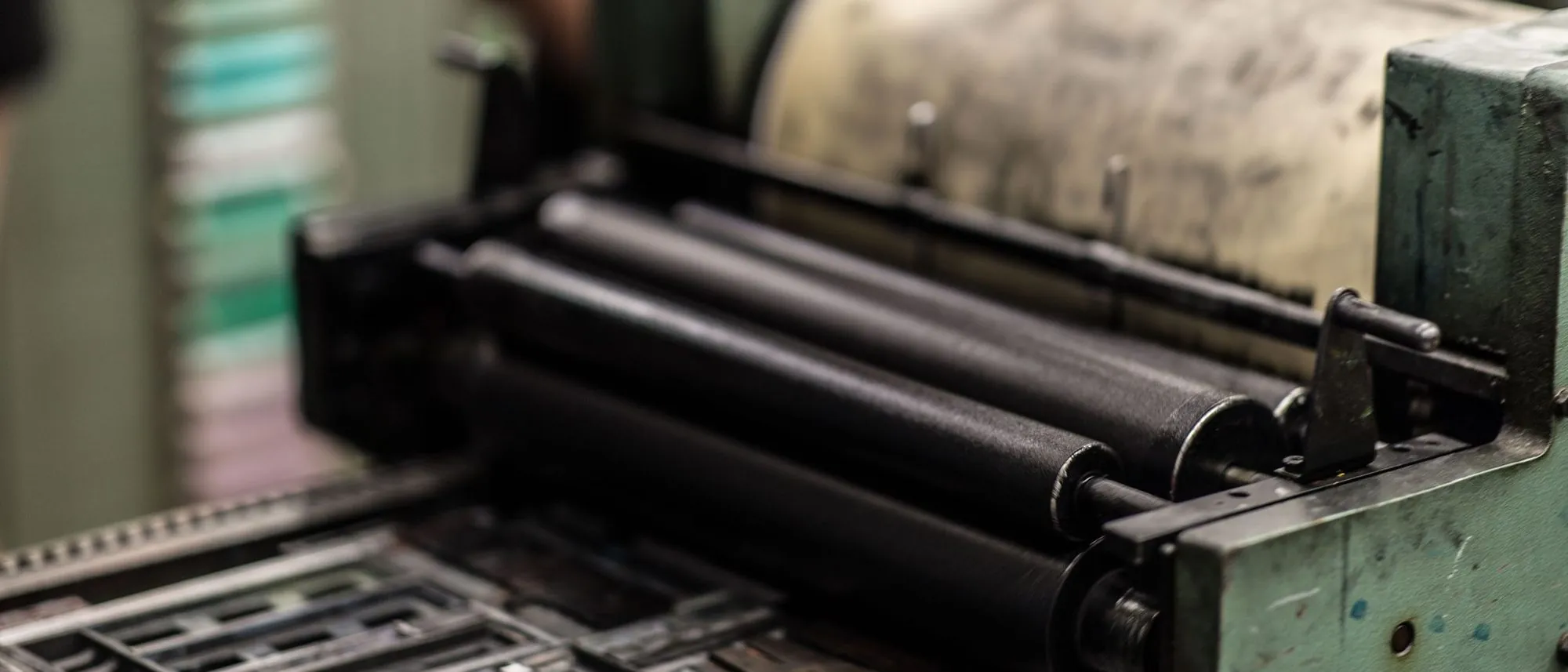 Close view of the rollers and gears of an industrial printing press.