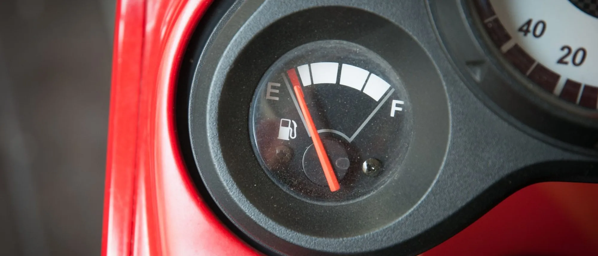 A car's fuel gauge needle sits close to the empty mark.