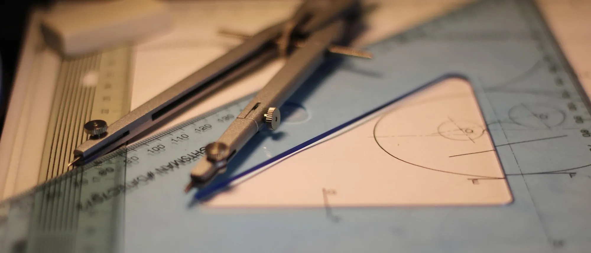 A compass and a set square resting on a sketchpad.
