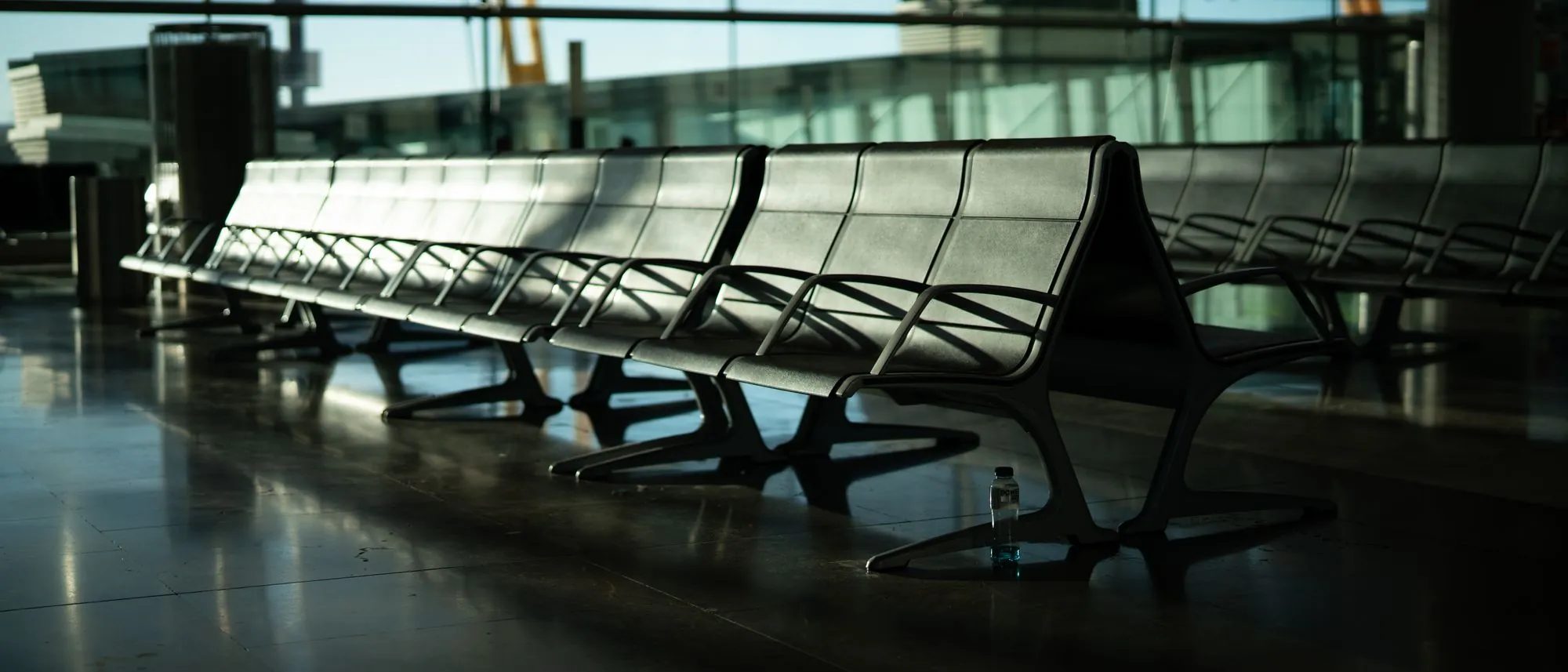 Empty metal benches in an airport terminal with low sun through the glass