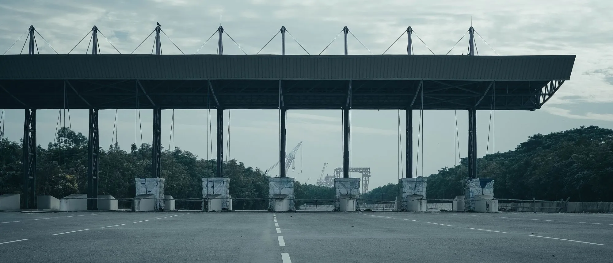 An empty toll gate on a deserted highway under an overcast sky