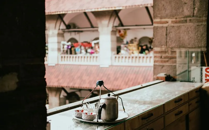 A market seen from behind a shop counter with a tea kettle and cups in the foreground.