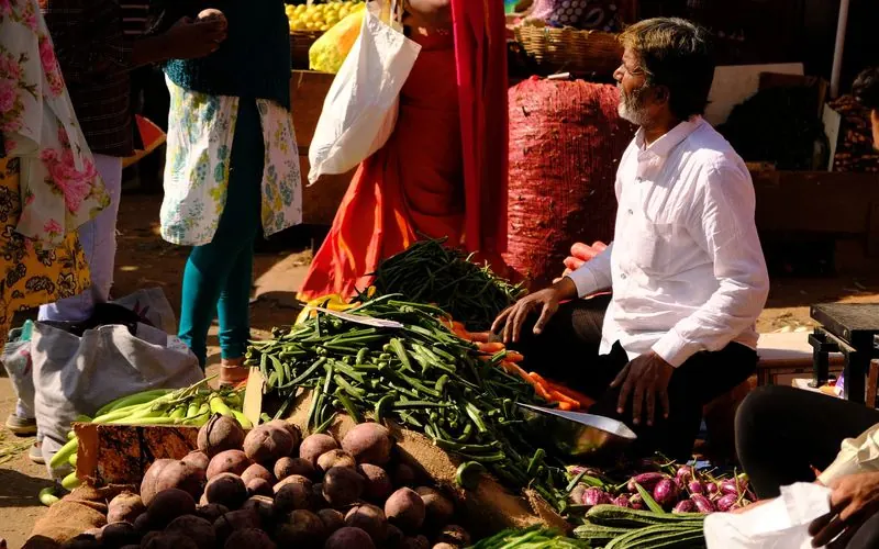 Shoppers move between produce stalls at a vegetable market in Bengaluru.