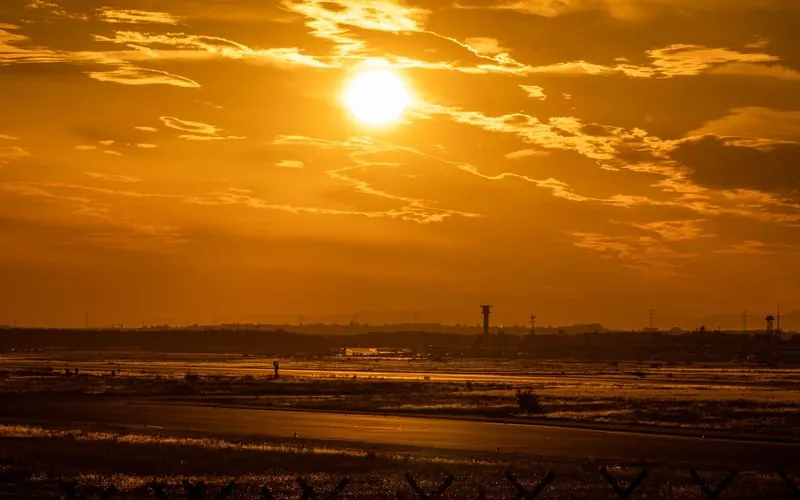 An airport runway under a golden sunset sky.