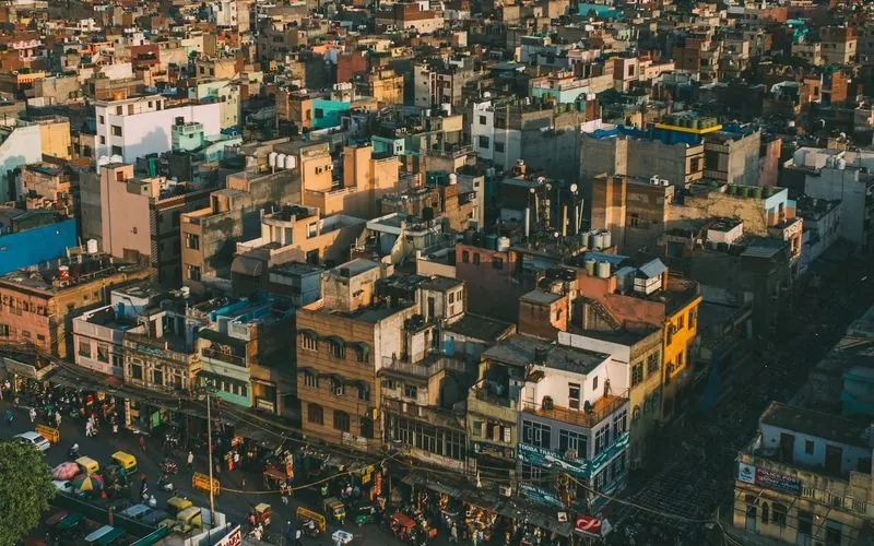 Aerial view of dense Old Delhi rooftops and a busy street in warm light