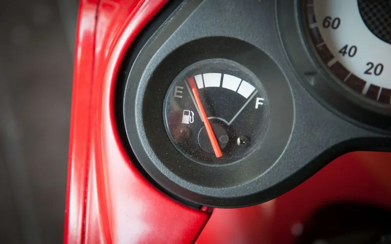 A car's fuel gauge needle sits close to the empty mark.