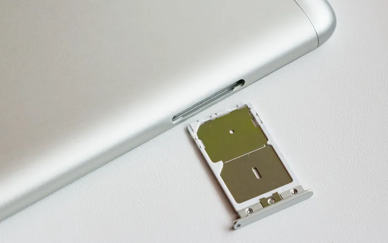 A dual SIM tray pulled out of the side of a silver smartphone