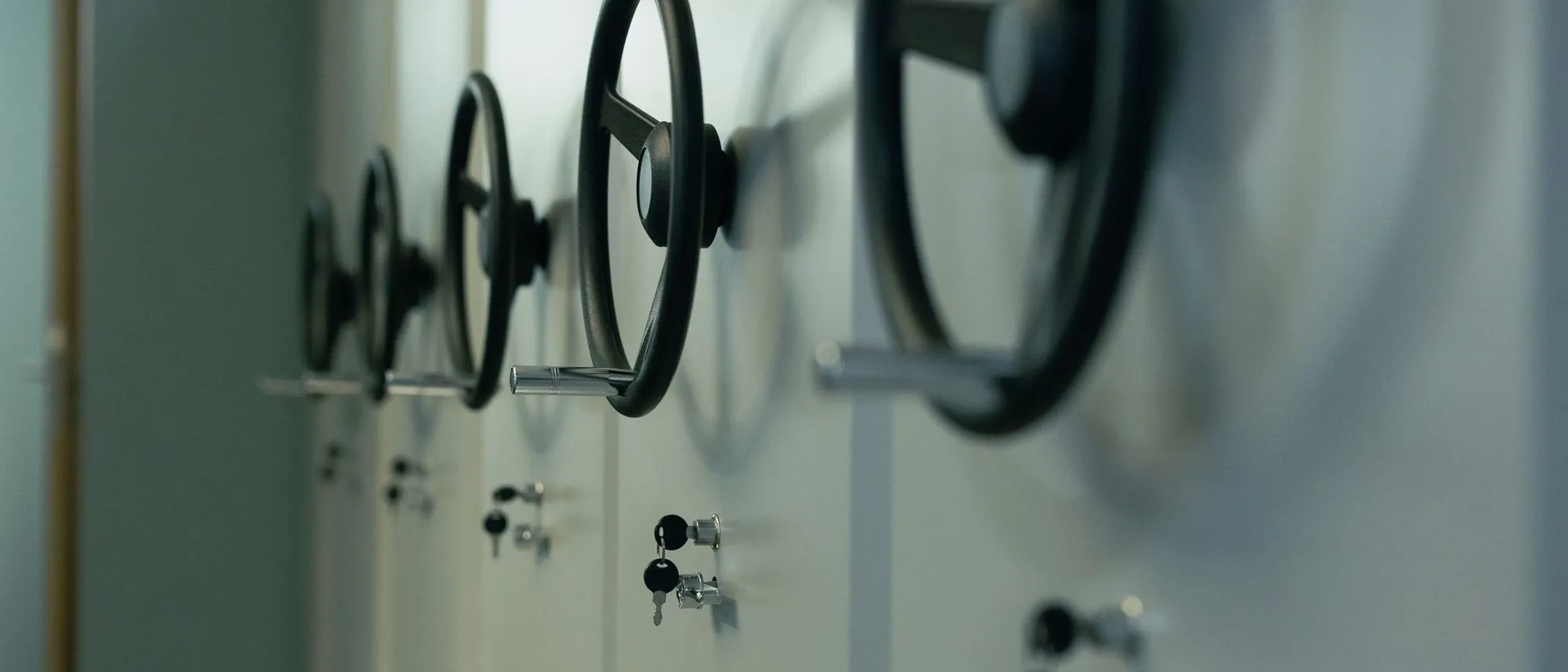 A row of steel safe doors with wheel handles and keys in their locks.