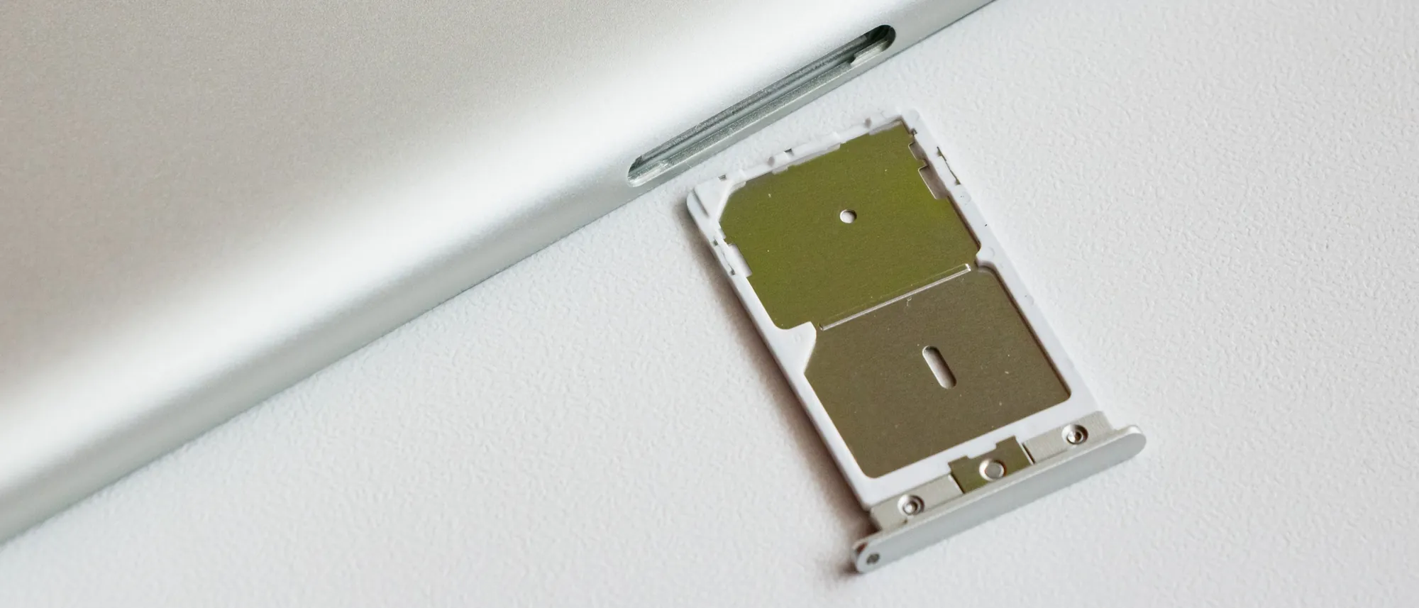 A dual SIM tray pulled out of the side of a silver smartphone