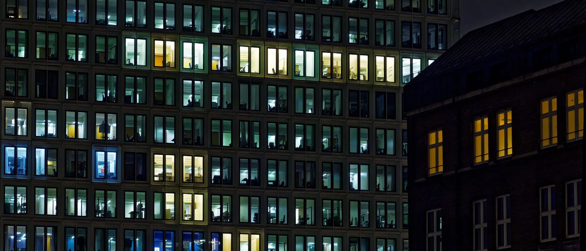 The glowing windows of an office building at night.